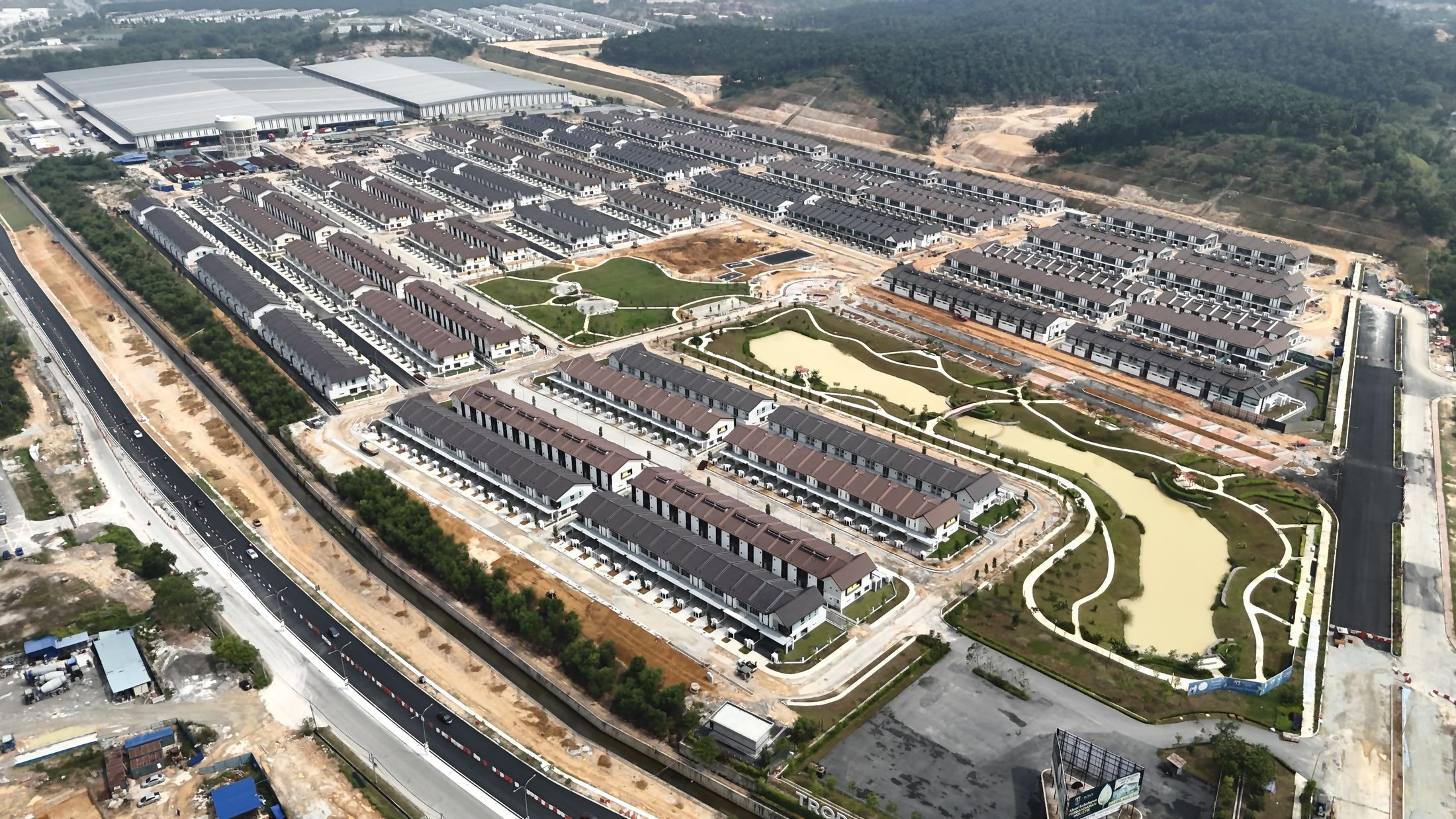 Aerial drone photo of Avisa Residences construction progress, taken 23 September 2026, showing completed terrace home rows, the lake and park
